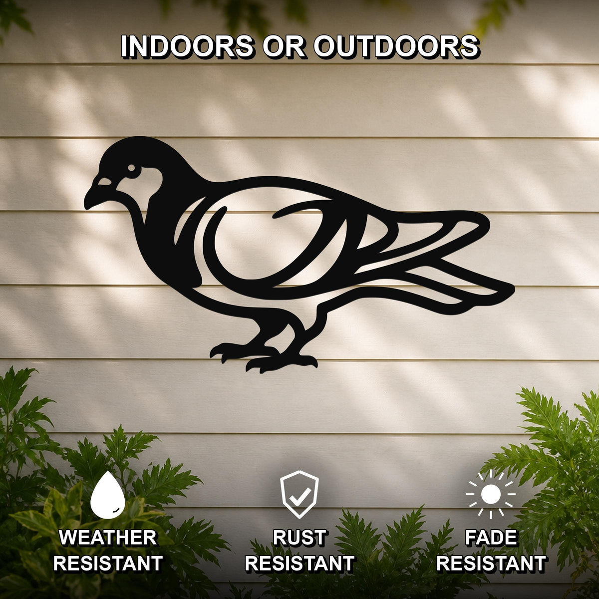 Black metal pigeon wall art silhouette with internal cutout details, mounted on a light-colored outdoor wall with greenery, weather resistant, rust resistant, and fade resistant.