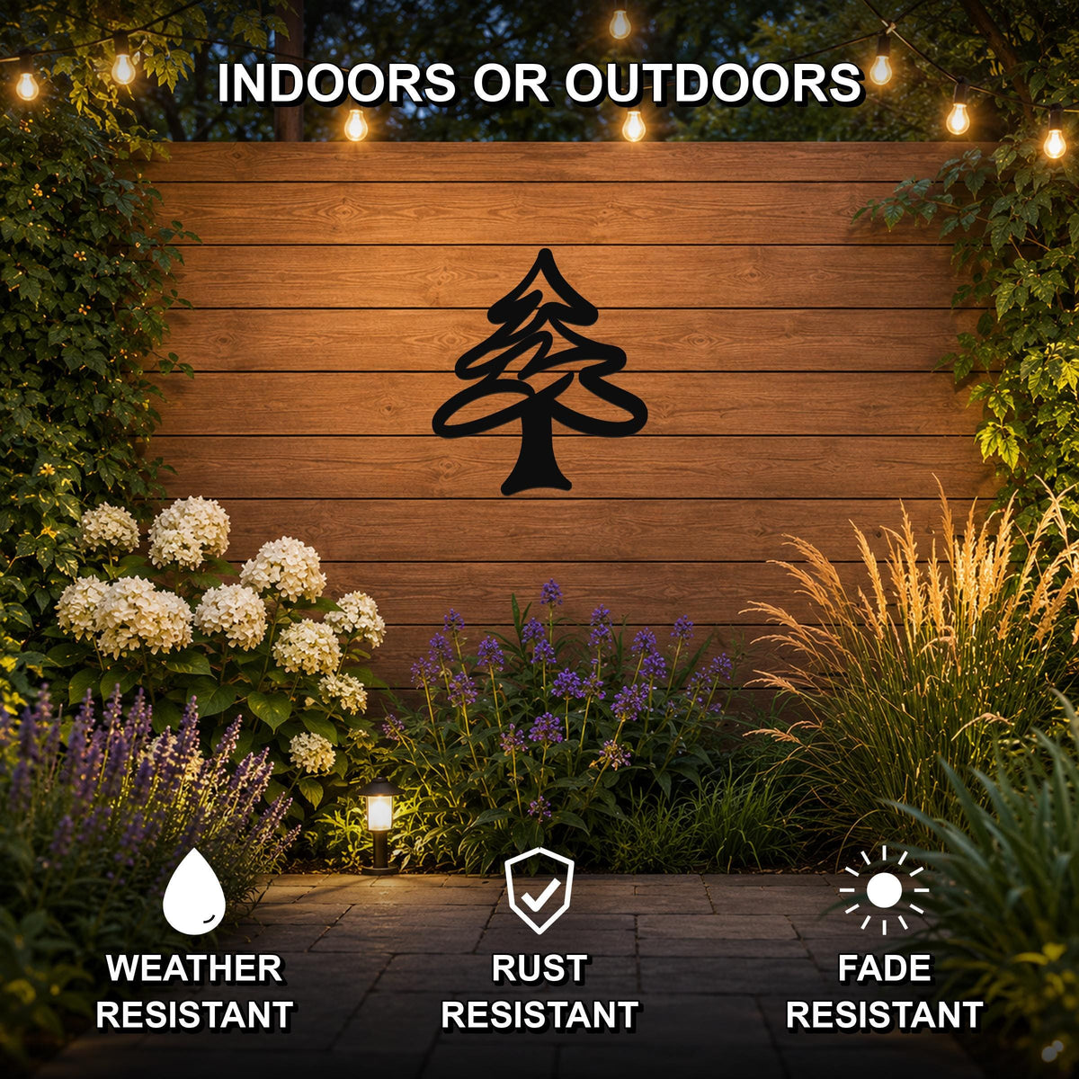 Black metal pine tree wall art silhouette mounted on a wooden outdoor wall, surrounded by plants and string lights, with text indicating it is weather, rust, and fade resistant.