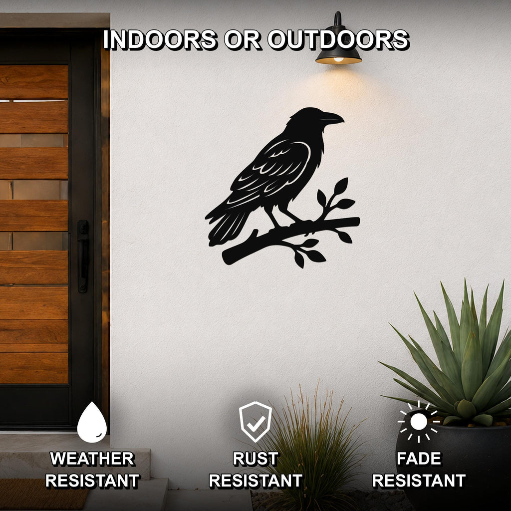 Black metal raven wall art silhouette perched on a branch, mounted on an outdoor wall beside a wooden door and potted plants.