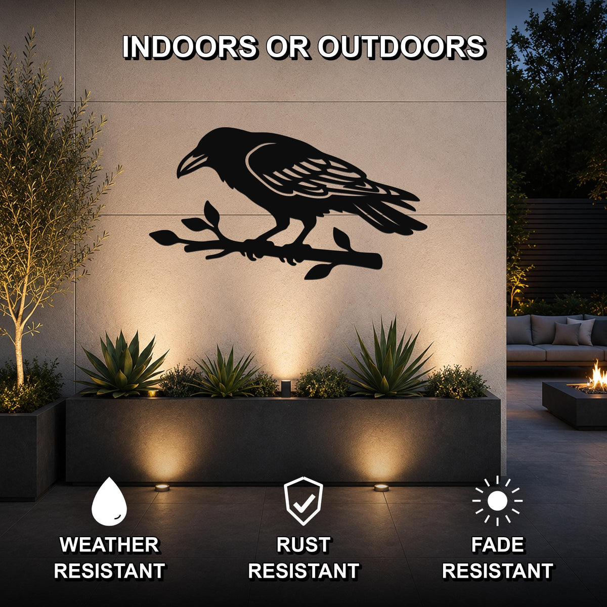 Black metal raven wall art cutout perched on a branch, mounted on an outdoor wall above a planter in a modern patio setting.