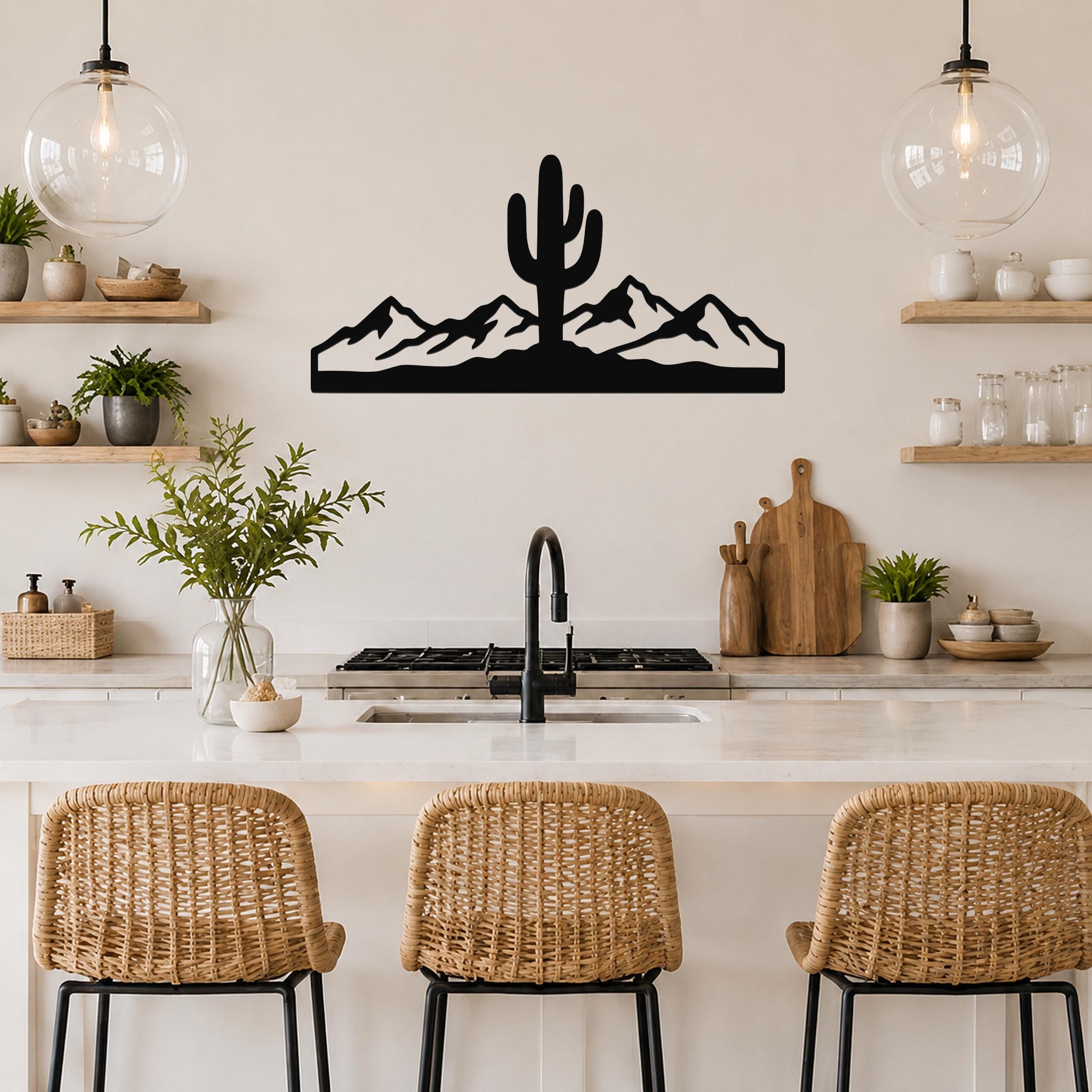Black metal wall art featuring a saguaro cactus and mountain silhouette, mounted above a kitchen counter.