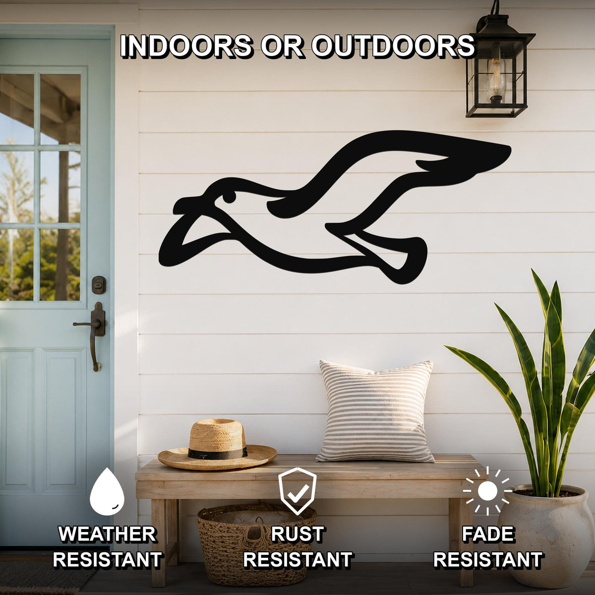 Black metal seagull wall art with motion-line cutouts, mounted on a white shiplap wall above a wooden bench in a porch setting.