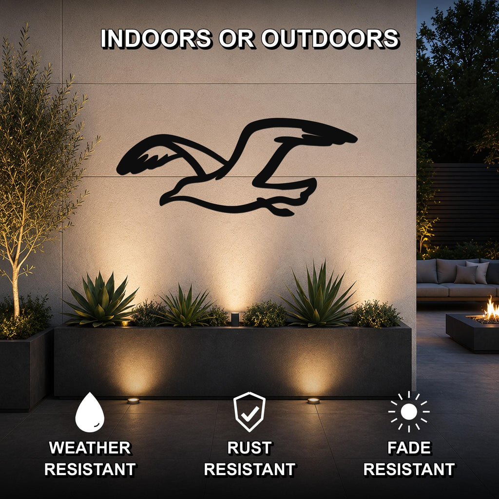 Black metal seagull wall art with motion-line cutouts, mounted on an outdoor wall above a planter in a modern patio setting.