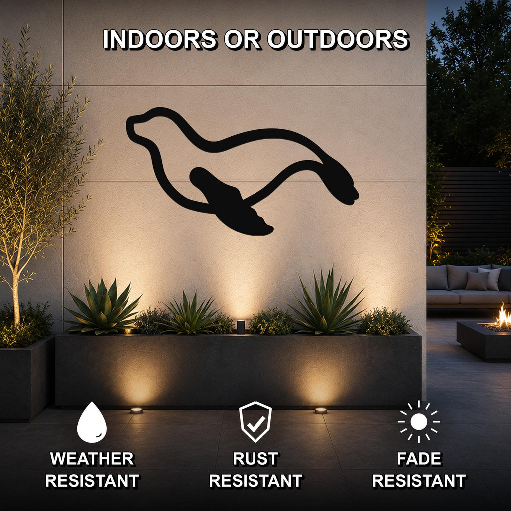 Black metal sea lion wall art silhouette mounted on an outdoor wall above a planter, with text indicating it is weather, rust, and fade resistant for indoor or outdoor use.