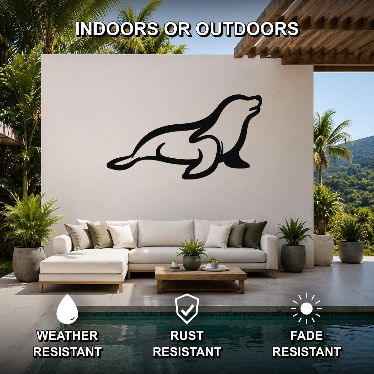 Black metal sea lion wall art silhouette mounted on a white outdoor wall above a white sectional sofa in a patio living area.