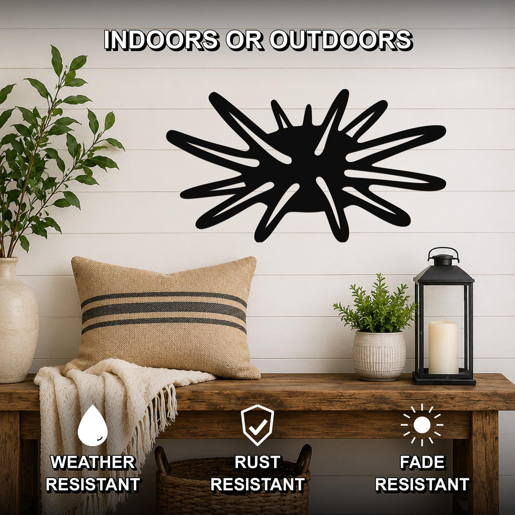 Black metal sea urchin wall art with spiky cutout design, mounted on a white shiplap wall above a wooden bench in a living room.