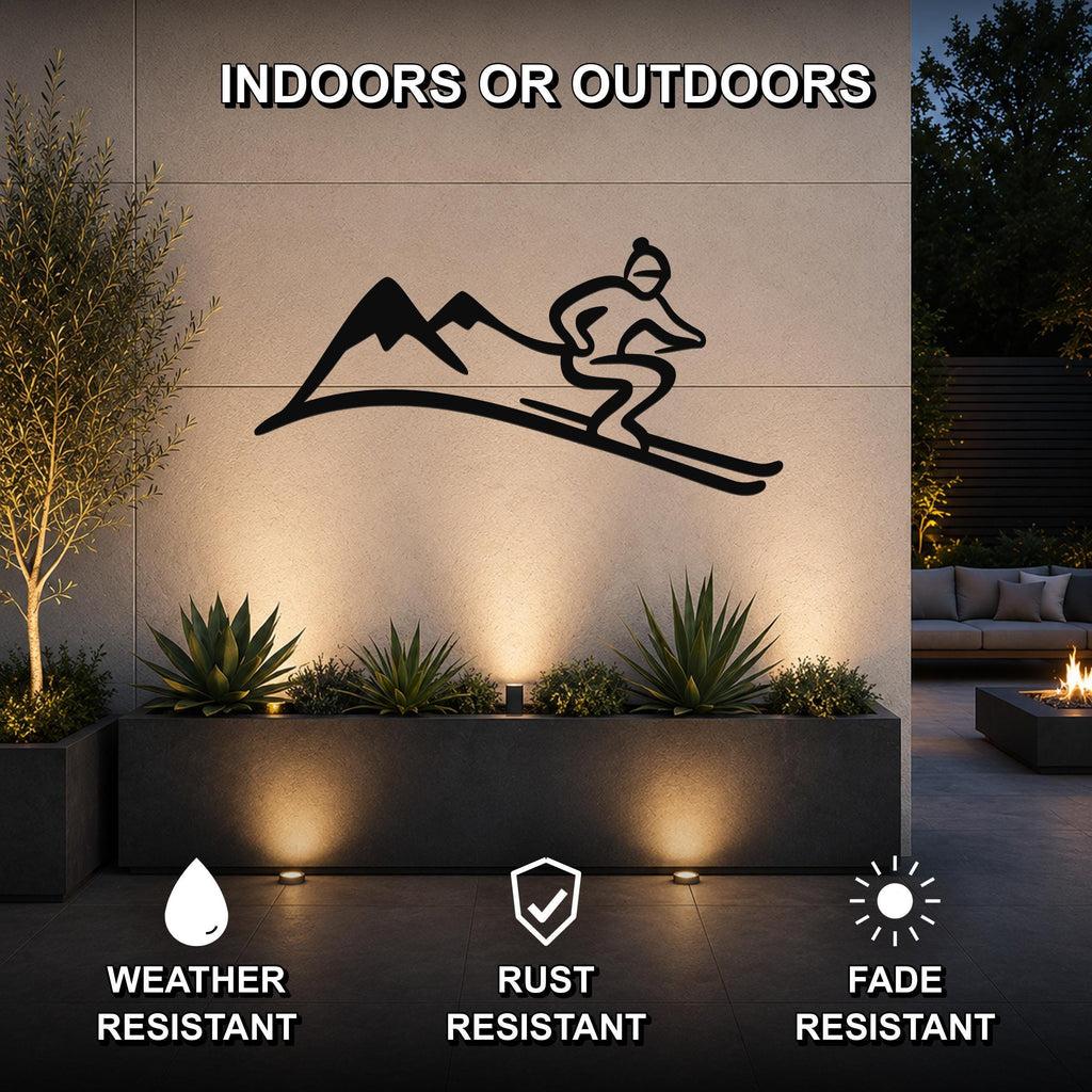 Black metal skier and mountain wall art silhouette mounted on an outdoor patio wall above a planter, with text indicating it is weather, rust, and fade resistant.