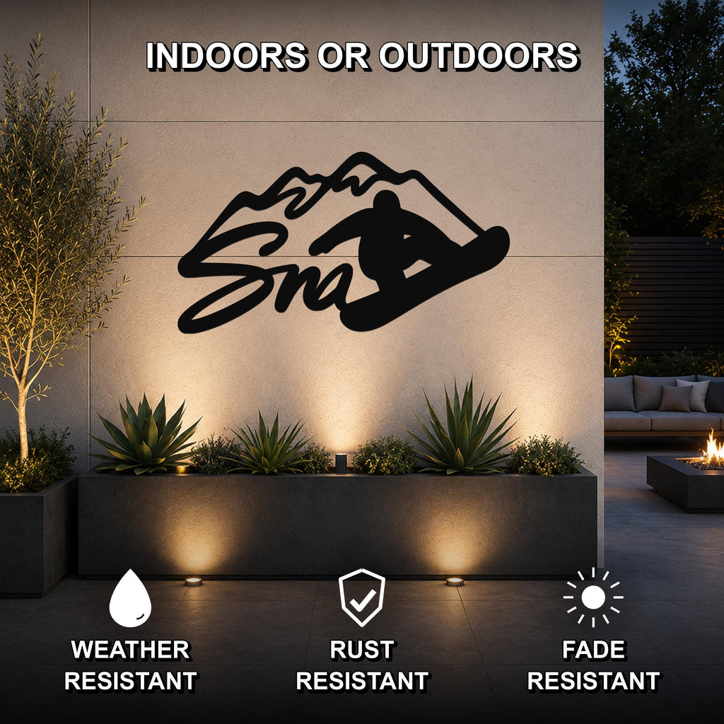 Black metal snowboarder silhouette wall art with mountain cutout, mounted on an outdoor patio wall above a planter with uplighting.