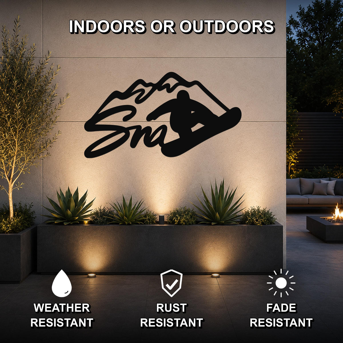 Black metal snowboarder silhouette wall art with mountain cutout, mounted on an outdoor patio wall above a planter with uplighting.