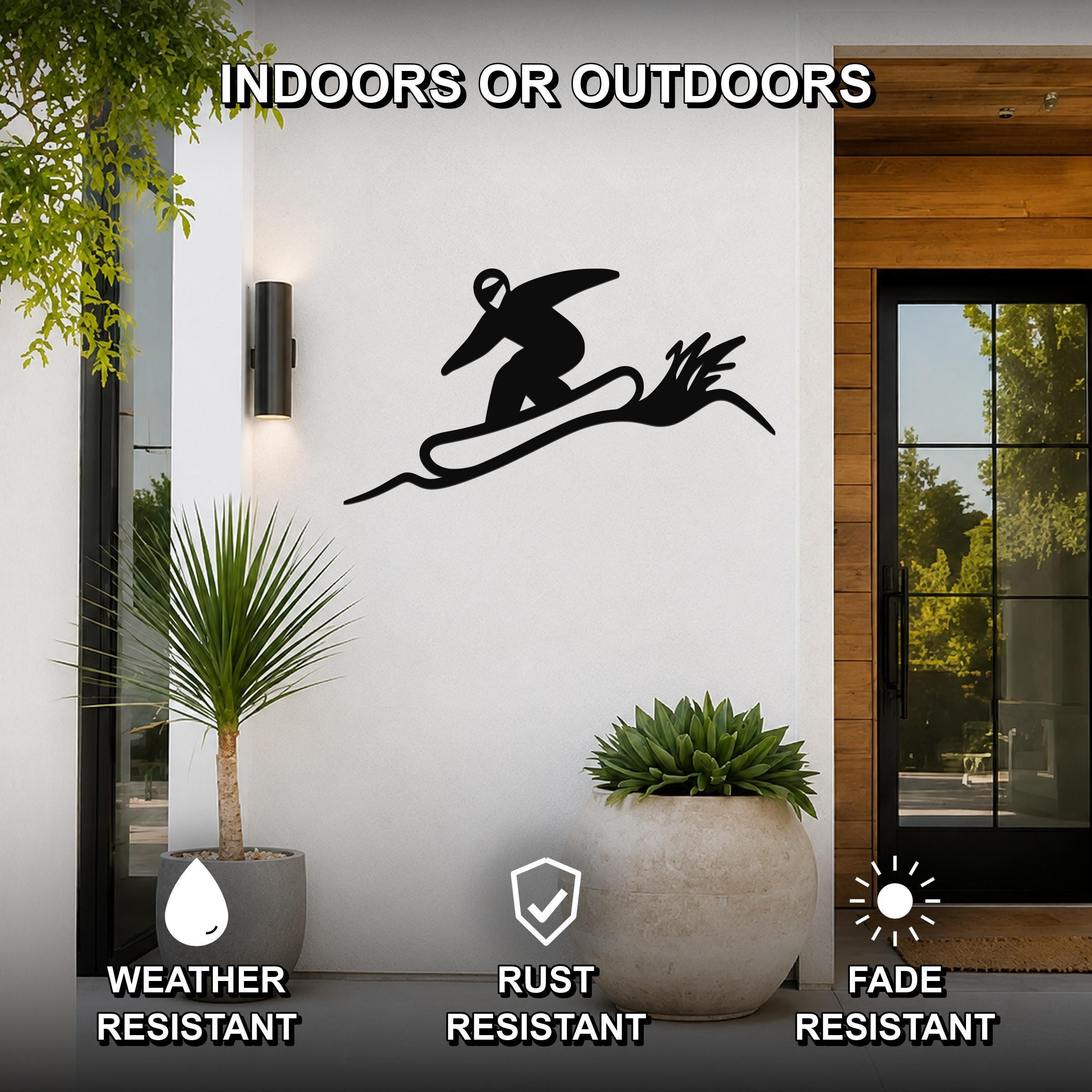 Black metal snowboarder wall sculpture with motion-line cutouts, mounted on a white exterior wall beside a glass door and potted plants.
