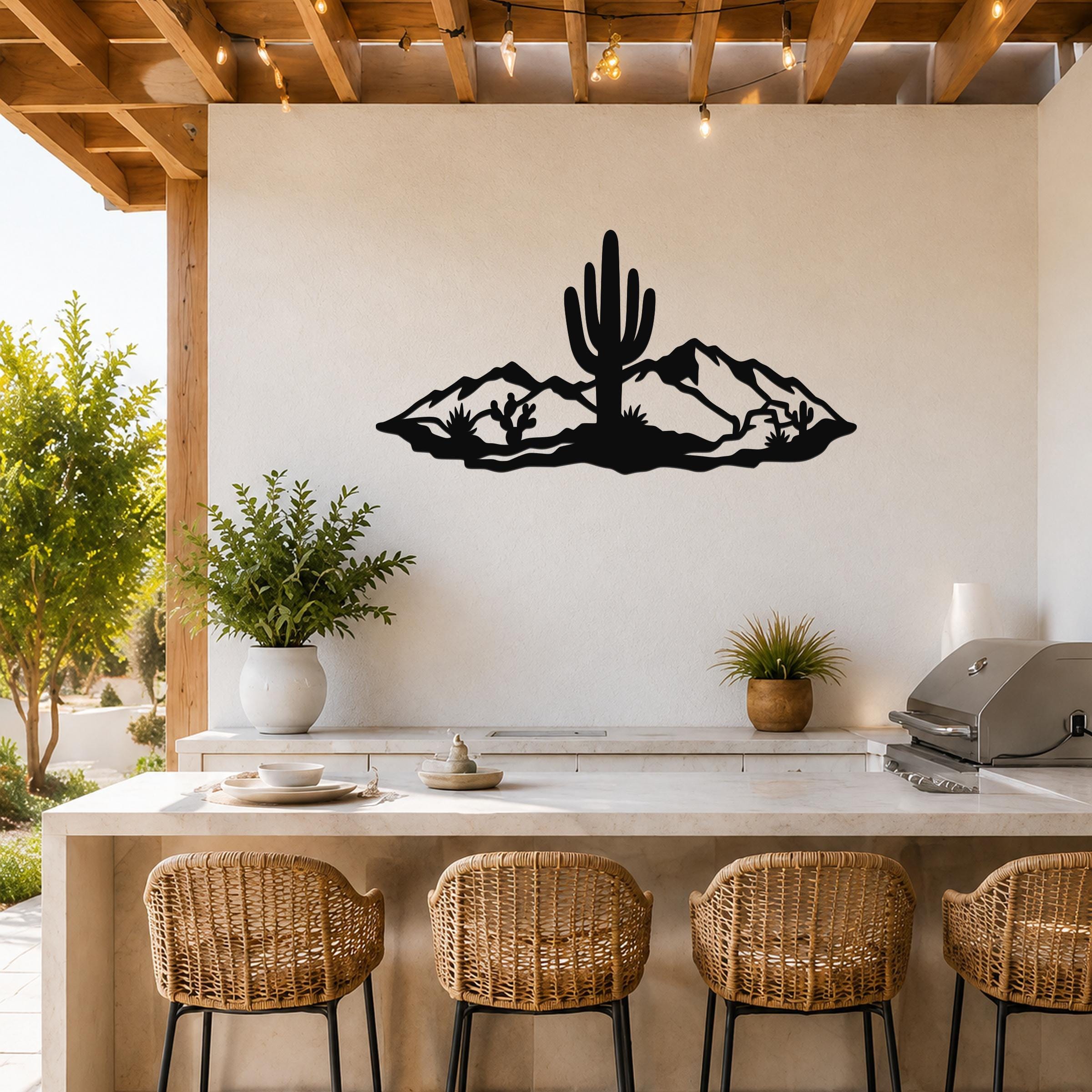 Black metal wall art featuring a desert silhouette with a saguaro cactus and mountains, mounted on a white wall above a kitchen counter.