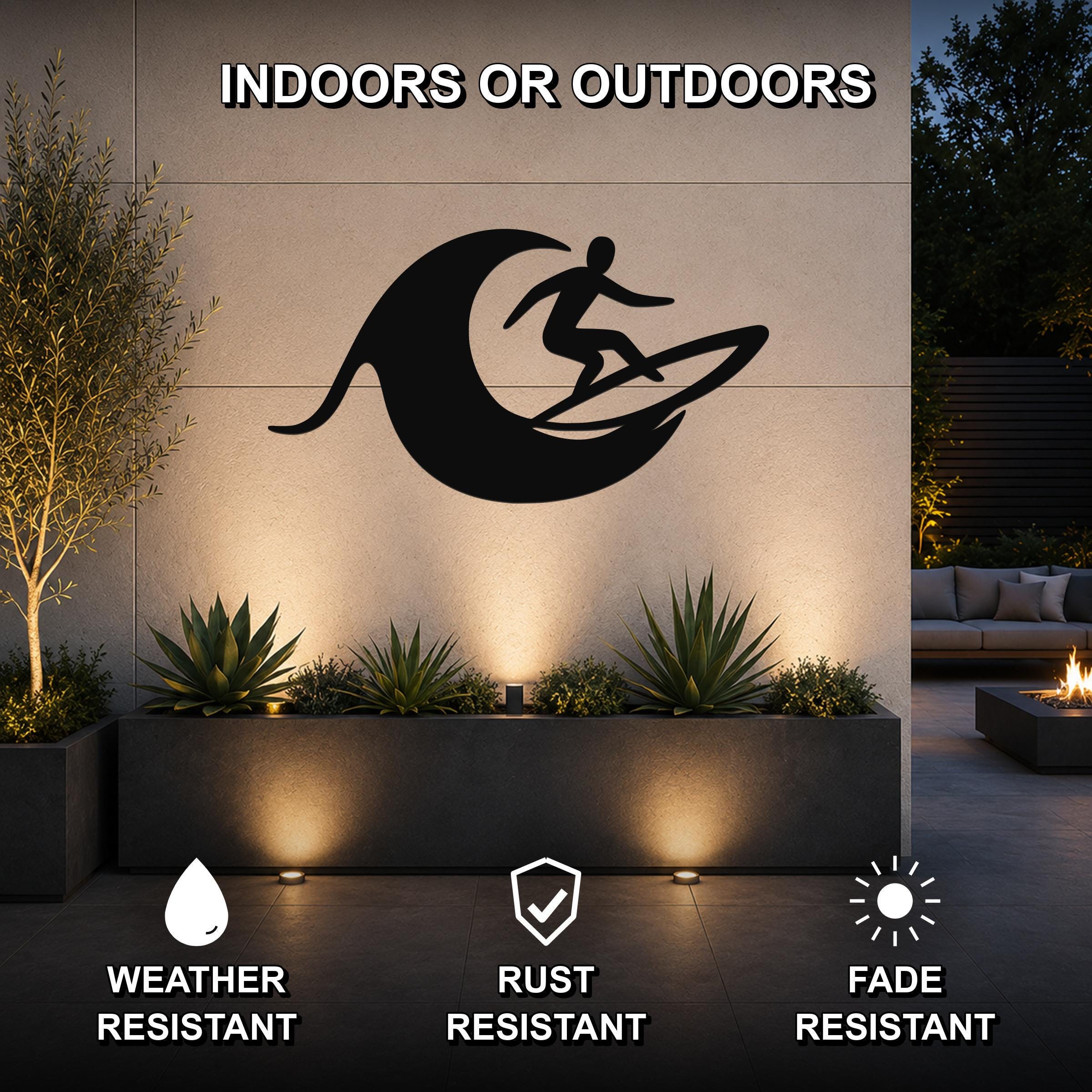 Black metal surfer wall art with a wave cutout, mounted on an outdoor patio wall above a planter with succulents.
