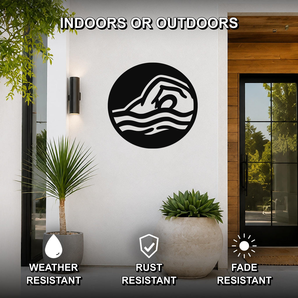 Black metal wall art featuring a swimmer silhouette in a circular design with wave cutouts, mounted on a white exterior wall beside a glass door and potted plants.