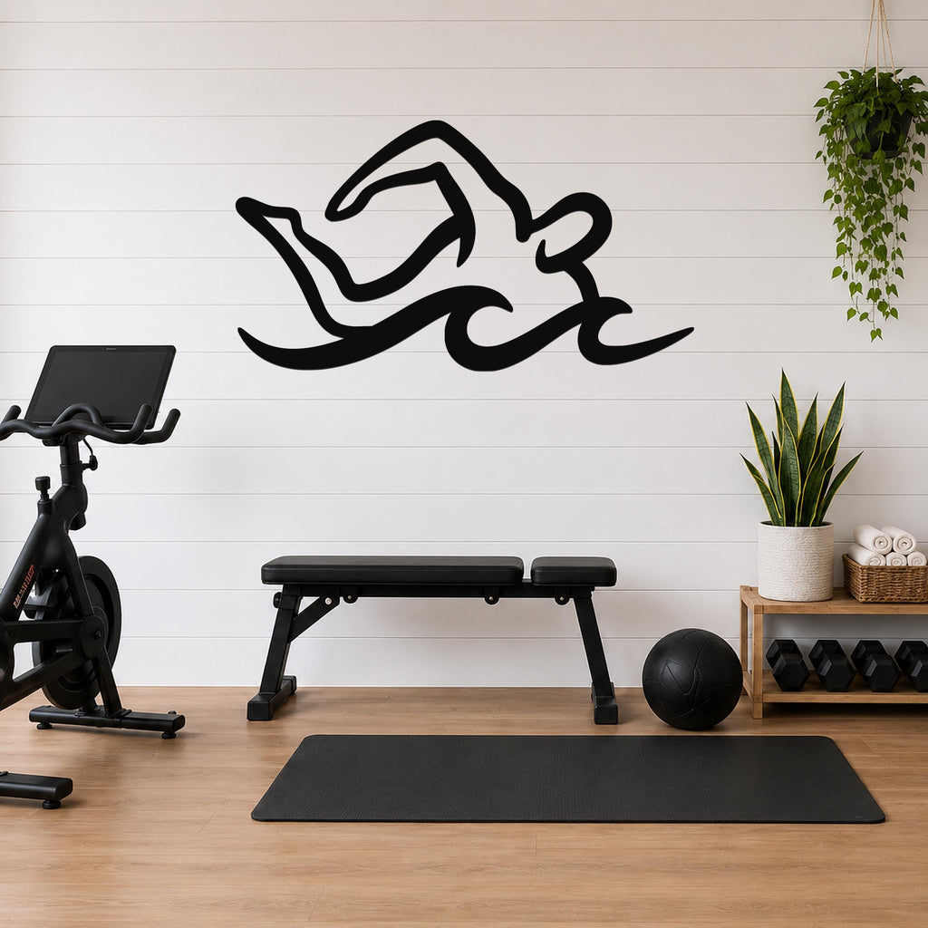 Black metal swimmer wall art with fluid motion cutouts, mounted on a white shiplap wall above a workout bench in a home gym.