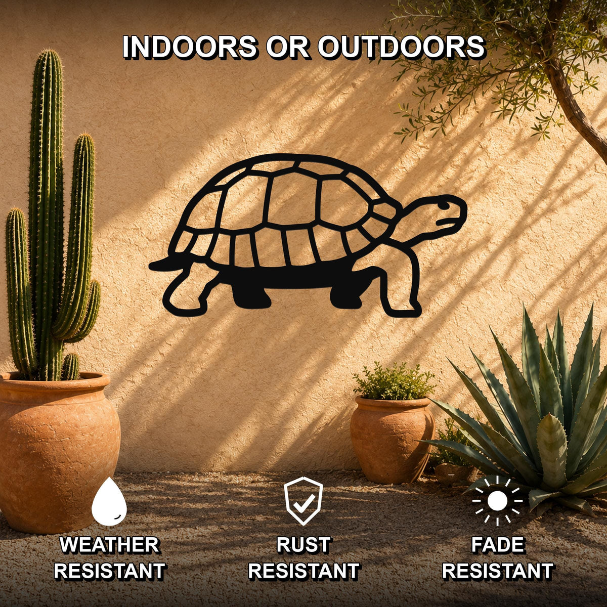 Black metal tortoise wall art with a cutout shell design, mounted on an outdoor stucco wall beside potted cacti and succulents.