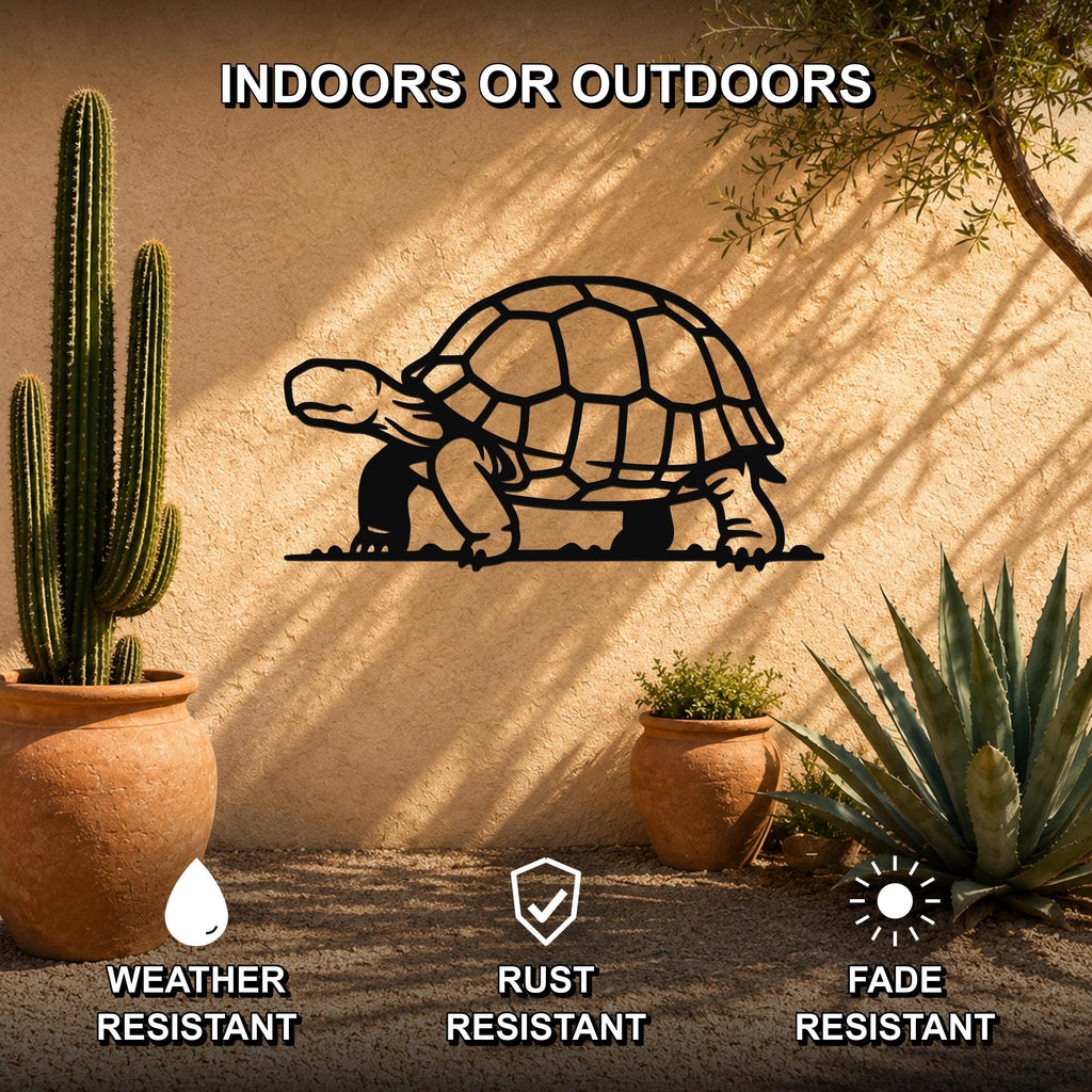 Black metal tortoise wall art with detailed shell cutouts, mounted on an outdoor stucco wall beside potted cacti and succulents.