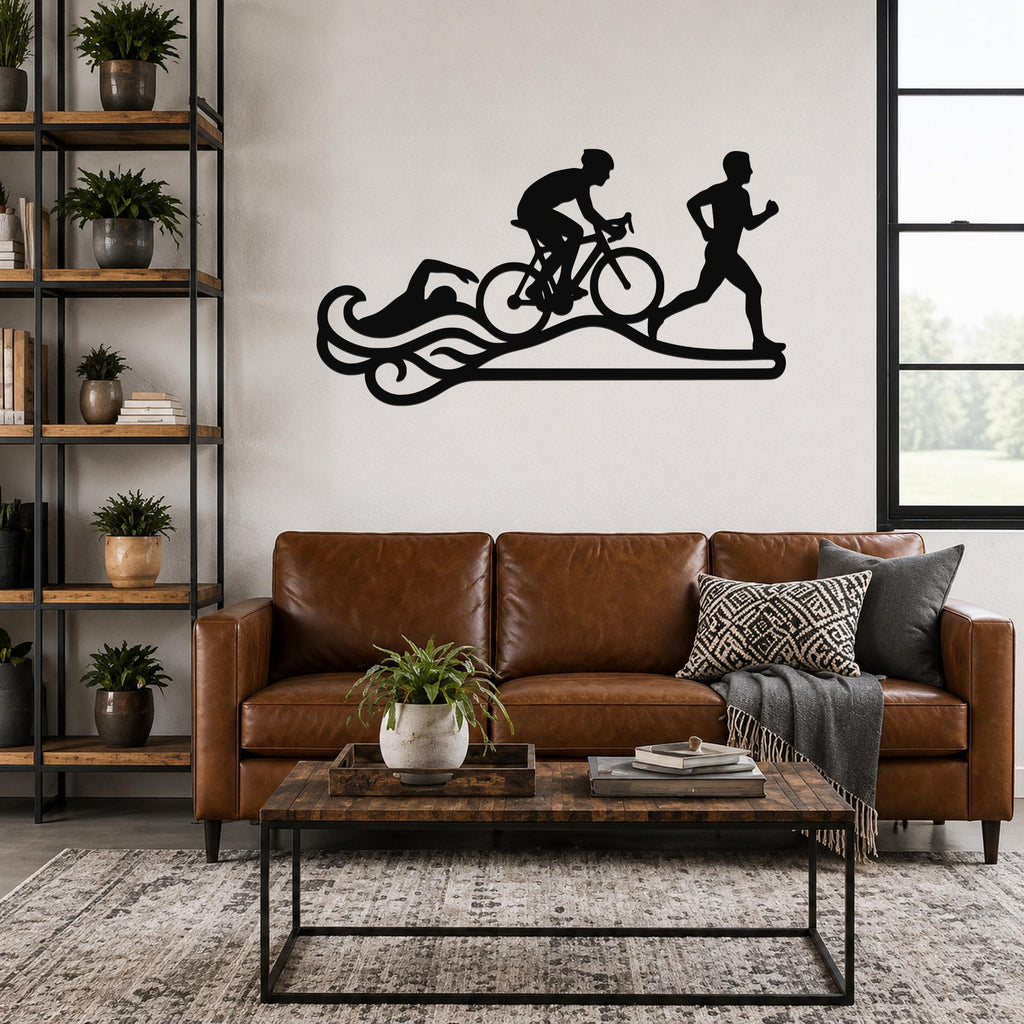 Black metal triathlon wall art with swim, bike, and run silhouettes on a wave design, mounted above a brown leather sofa in a living room.