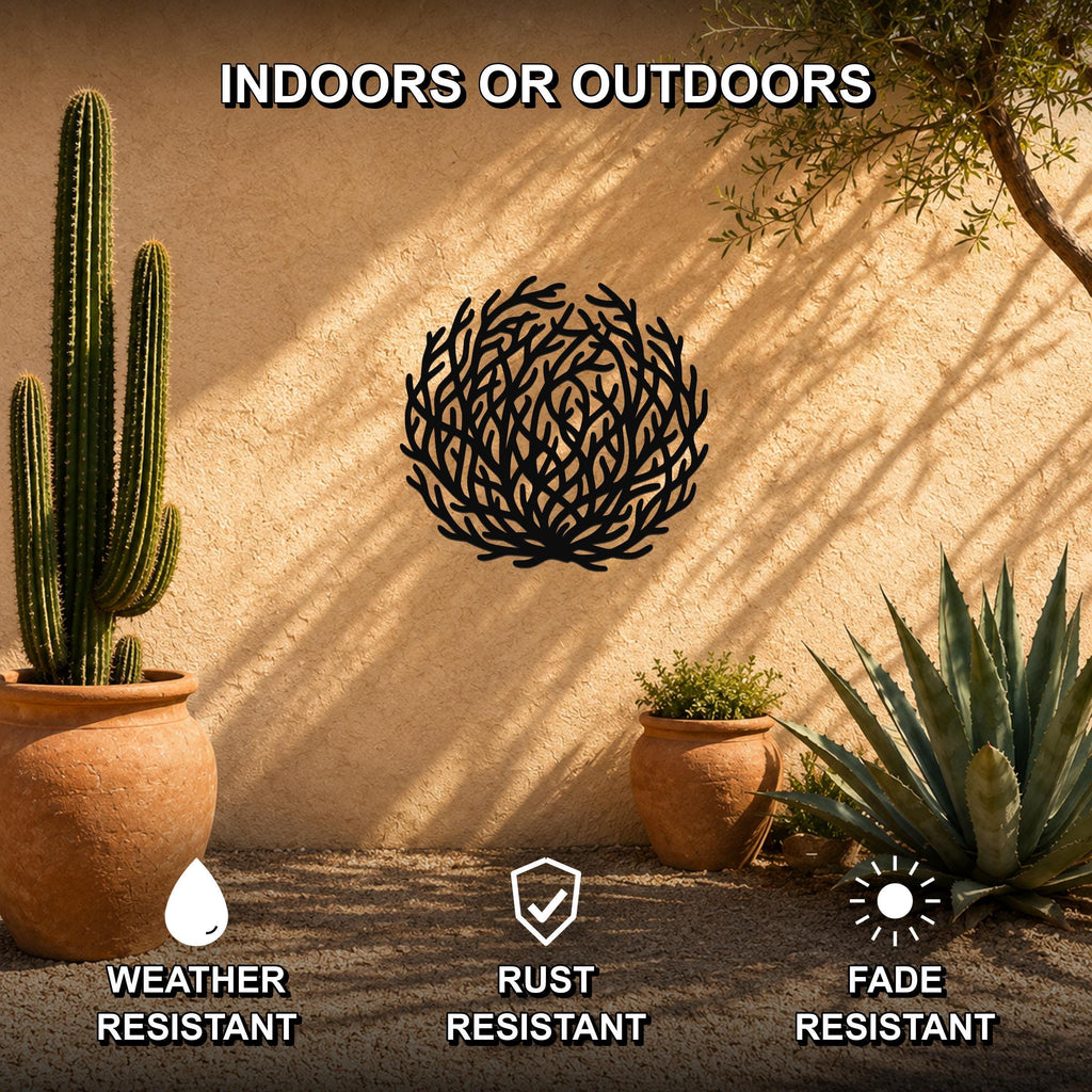 Black metal tumbleweed wall art with intricate branch cutouts, mounted on a stucco outdoor wall among potted cacti and succulents.
