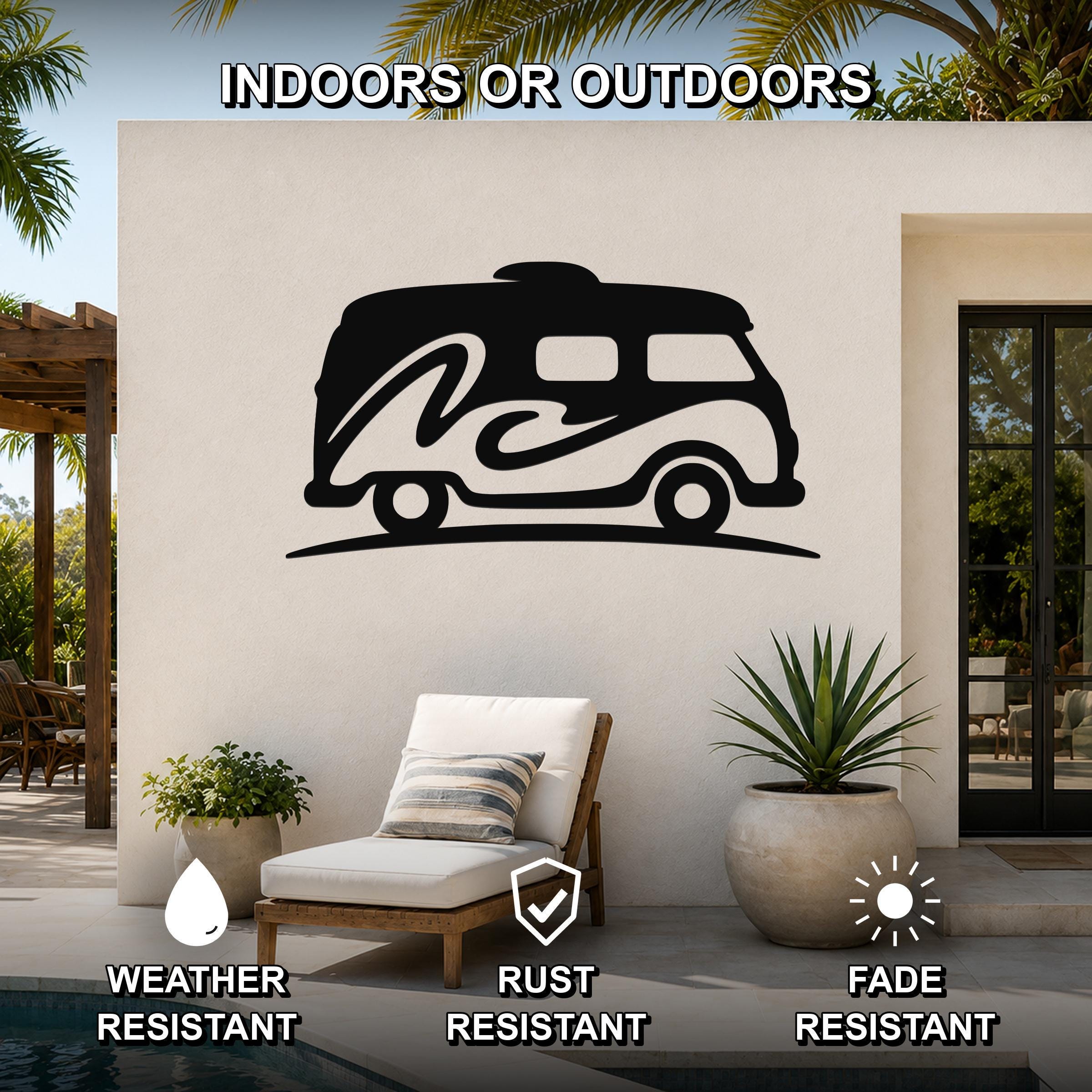 Black metal wall art silhouette of a vintage camper van with wave cutouts, mounted on an outdoor patio wall above a lounge chair.
