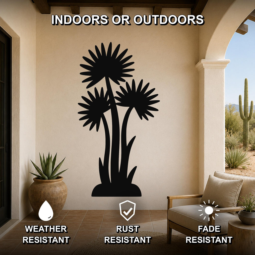 Black metal wall art featuring a silhouette of three desert flowers with spiky petals and long stems, mounted on a beige outdoor patio wall above a potted succulent and a wooden chair.