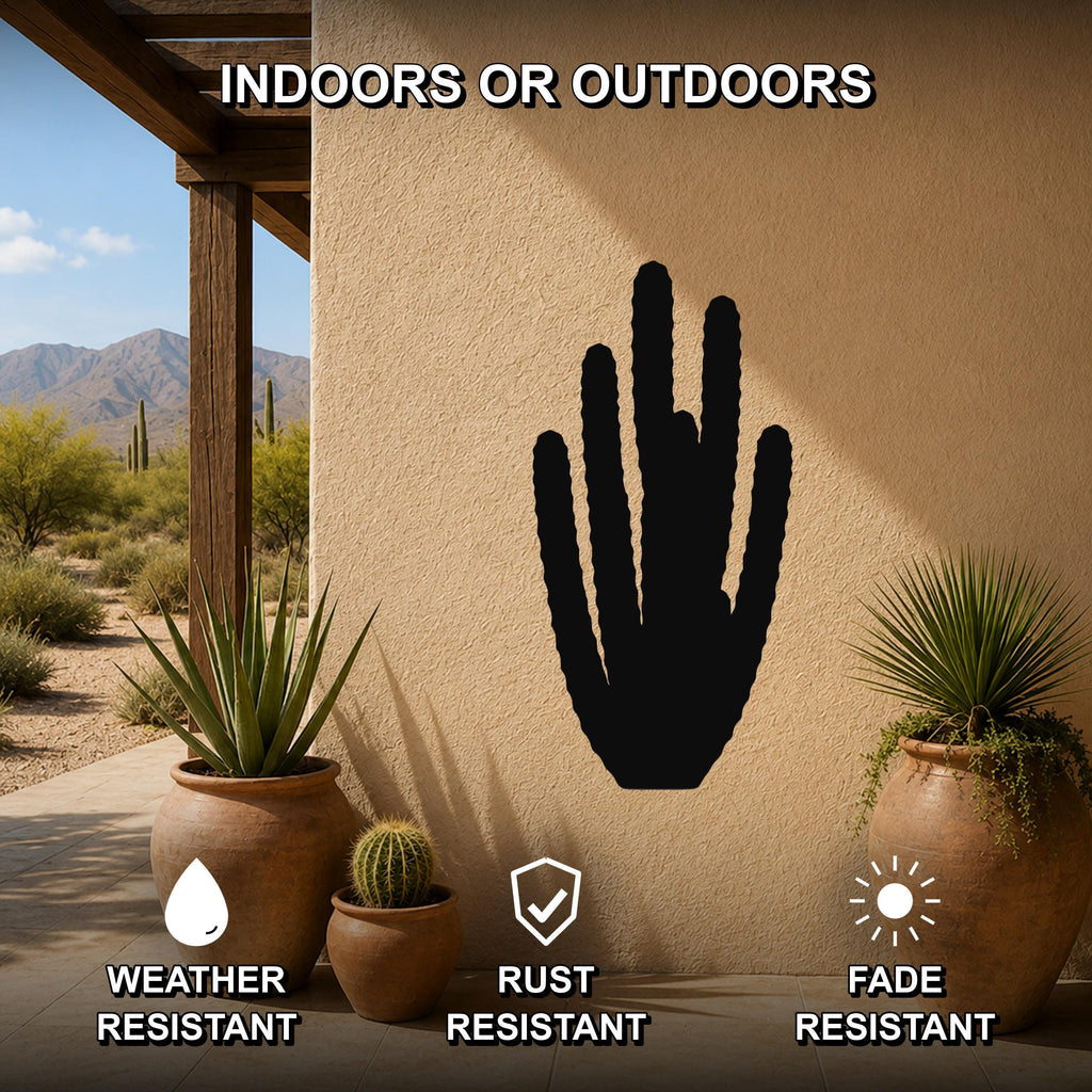 Black metal organ pipe cactus wall art silhouette mounted on a beige outdoor wall, displayed on a patio with potted plants and desert scenery in the background.