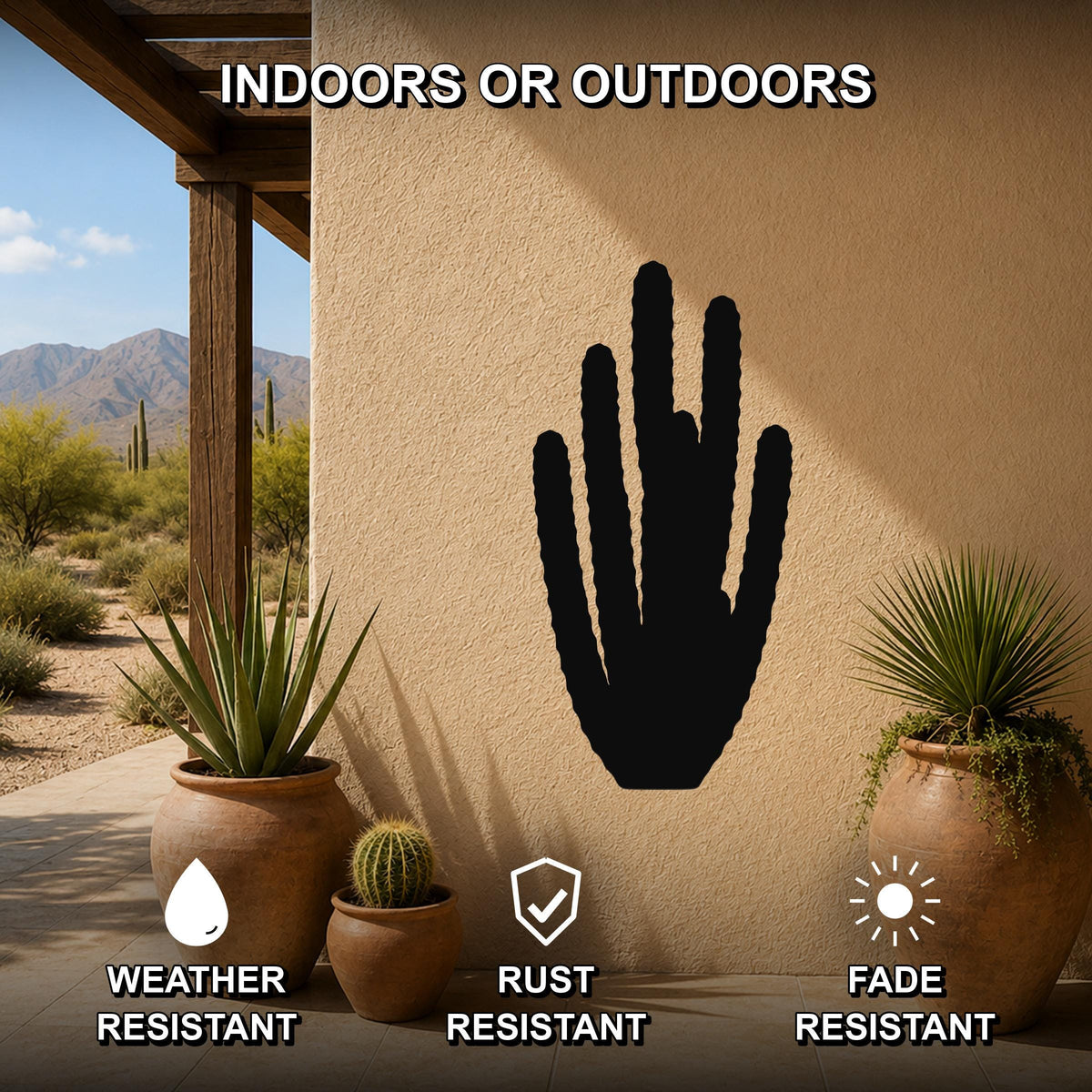 Black metal organ pipe cactus wall art silhouette mounted on a beige outdoor wall, displayed on a patio with potted plants and desert scenery in the background.