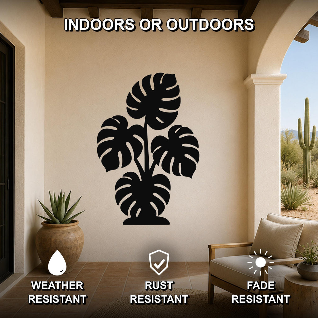 Black metal monstera plant wall art with leaf cutouts, mounted on a beige outdoor patio wall above a chair and potted plant.