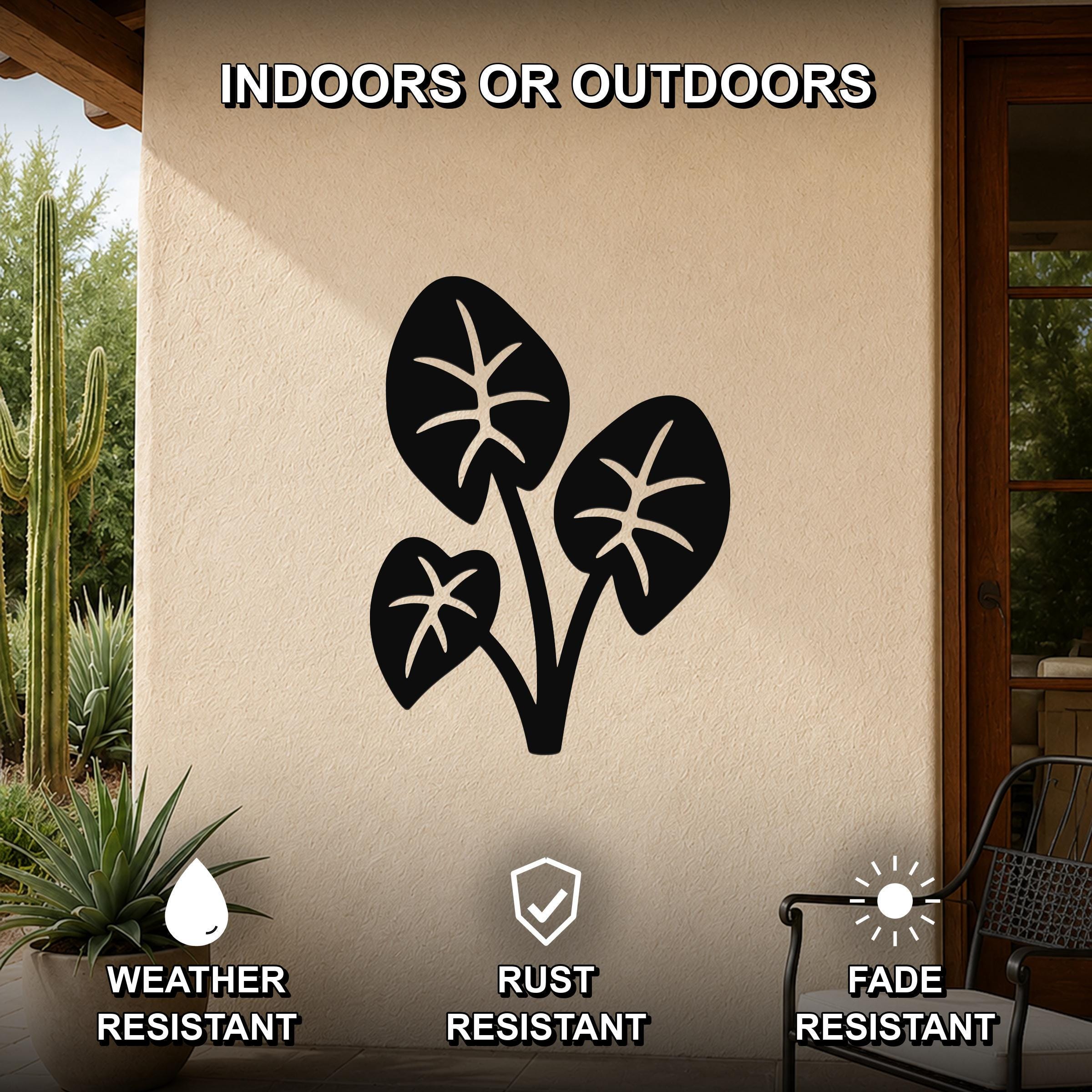 Black metal wall art featuring a cutout design of three elephant ear leaves, mounted on an outdoor patio wall with cactus and potted plant in view.