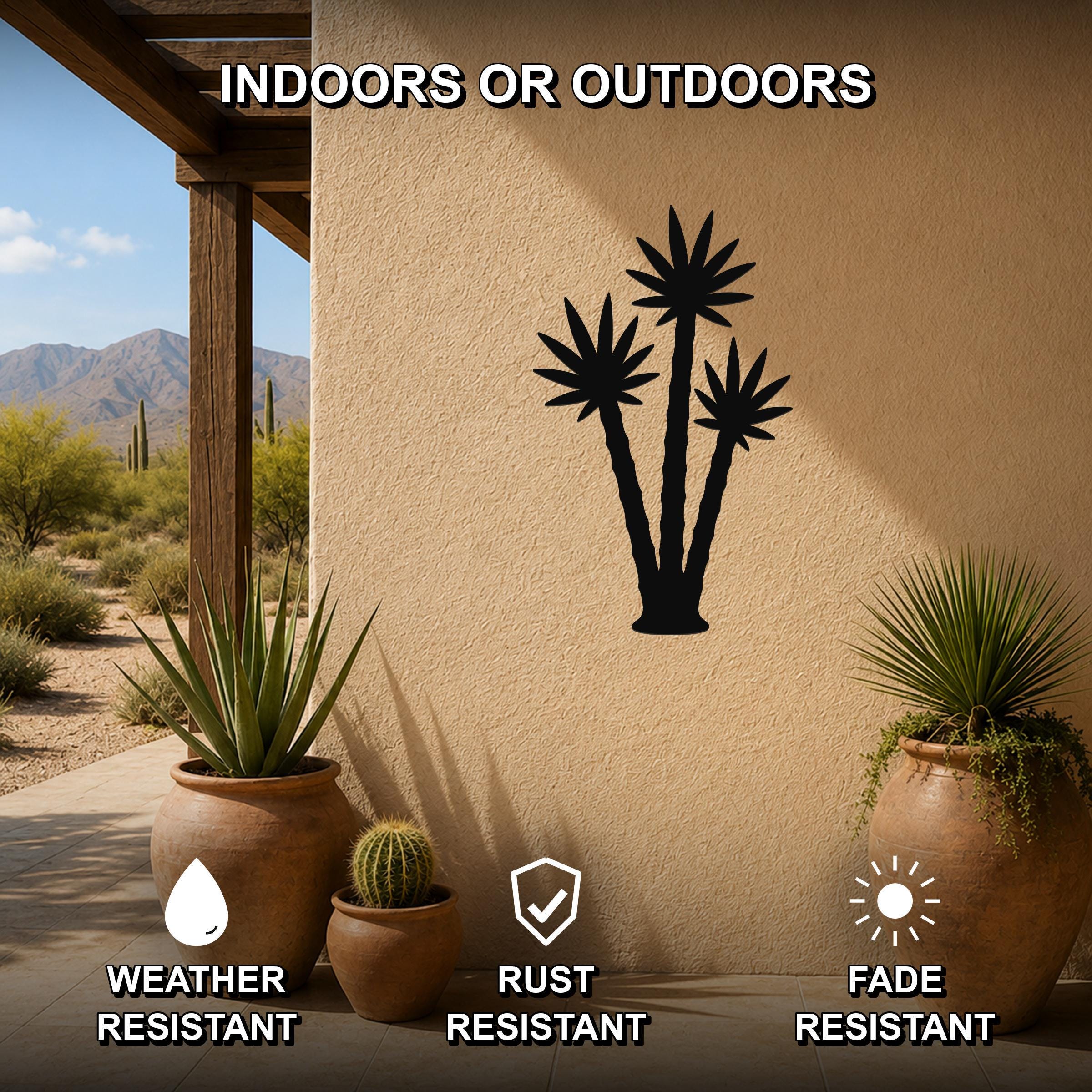 Black metal wall art featuring a silhouette of three desert plants, mounted on an outdoor wall beside potted succulents on a patio.