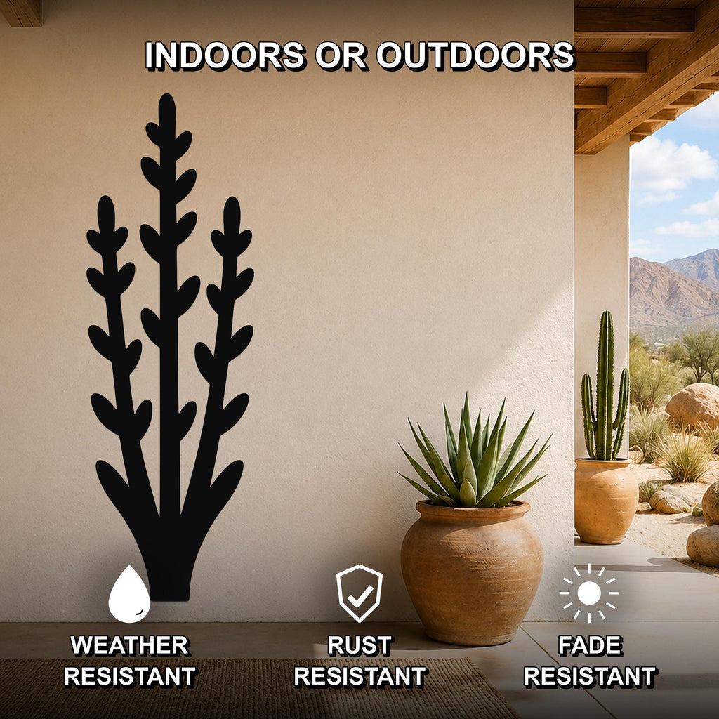 Black metal wall art in a desert plant silhouette design, mounted on a beige outdoor wall above a potted succulent, with text indicating it is weather, rust, and fade resistant.