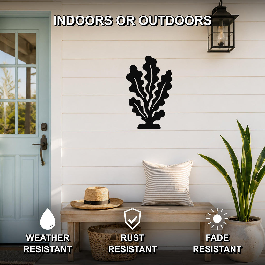Black metal kelp wall art with leafy cutouts, mounted on a white shiplap wall above a wooden bench on a porch.