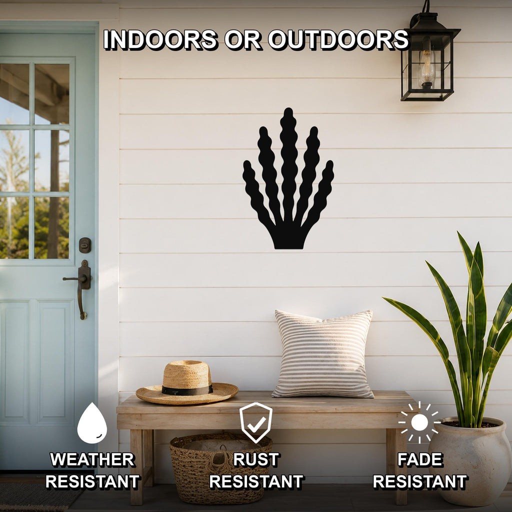 Black metal kelp wall art with wavy frond cutouts, mounted on a white shiplap wall above a wooden bench in a coastal entryway.