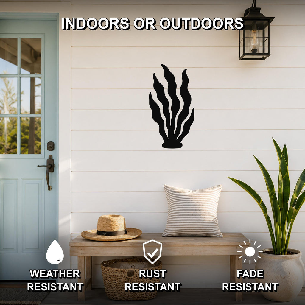 Black metal kelp wall art with flowing leaf cutouts, mounted on a white shiplap wall above a wooden bench on a porch.