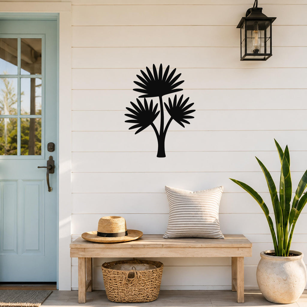 Black metal cutout palm tree wall art with three fan-shaped fronds, mounted on a white shiplap wall above a wooden bench on a porch.