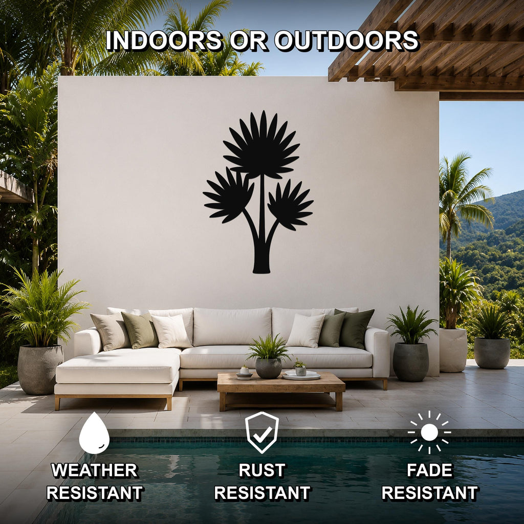 Black metal wall art of a fan palm tree silhouette, mounted on a white outdoor wall above a sofa in a patio living area.