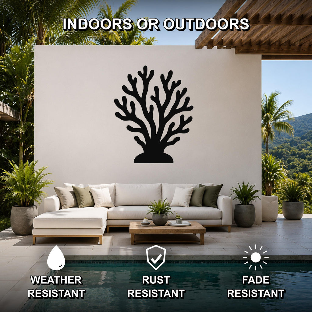 Black metal coral wall art with branching cutouts, mounted on a white outdoor wall above a sofa in a patio living area.