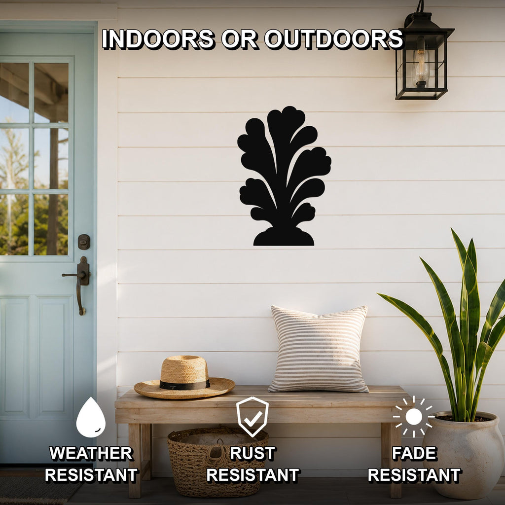Black metal coral wall art with leafy cutout design, mounted on a white shiplap wall above a wooden bench on a porch.