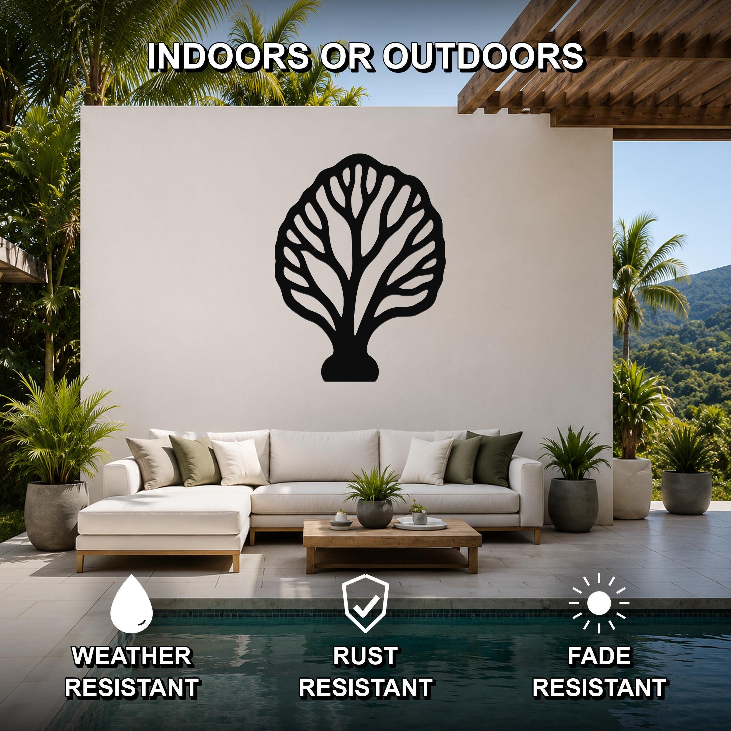 Black metal fan coral wall art with intricate branch cutouts, mounted on a white outdoor wall above a sofa in a patio living area.