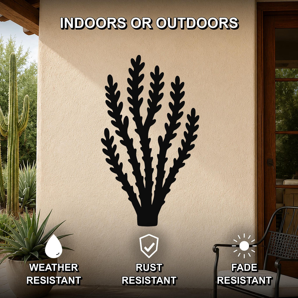 Black metal wall art in a desert branch silhouette, mounted on an outdoor patio wall with cacti and a chair visible nearby.
