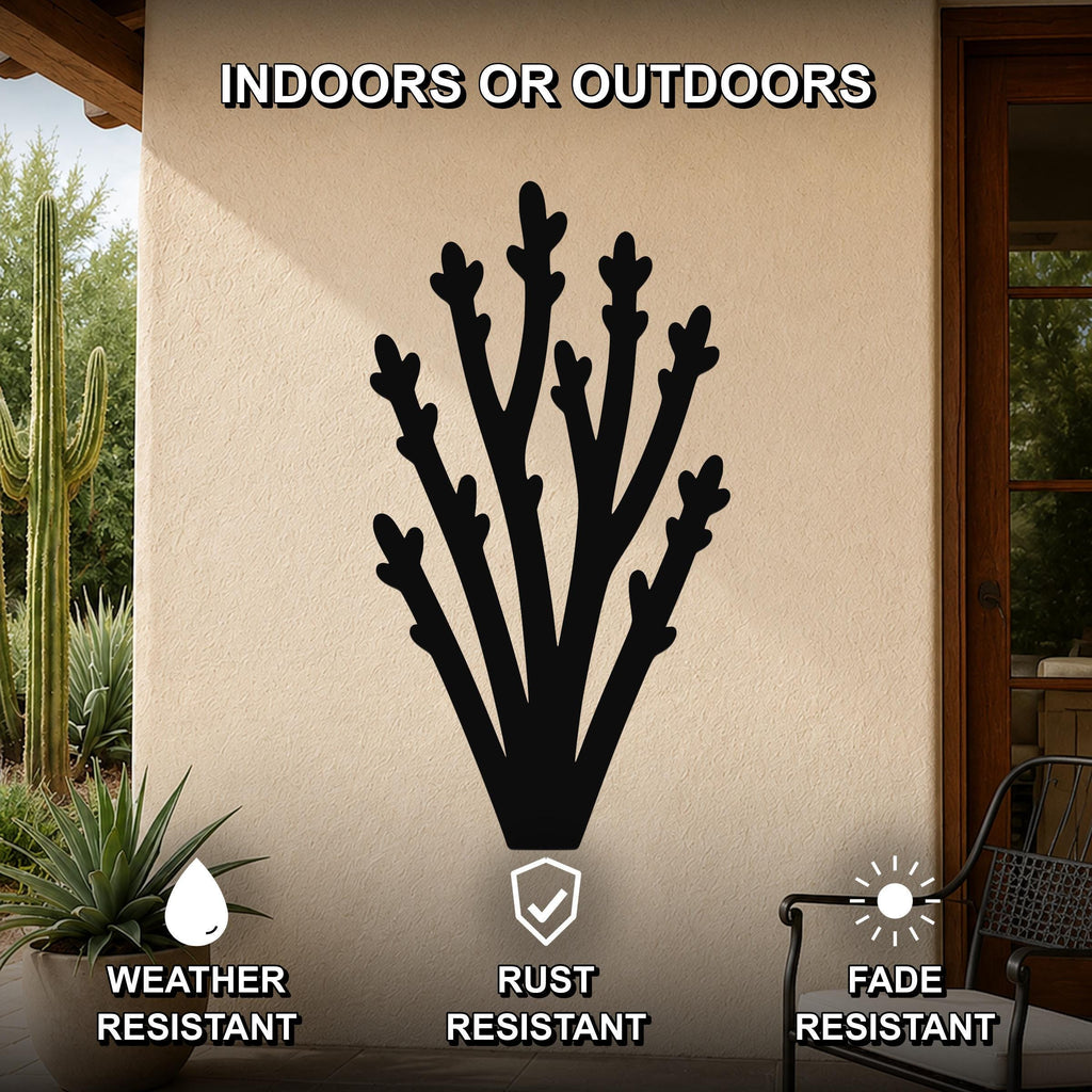 Black metal desert branch wall art with branching cutouts, mounted on an outdoor patio wall with cacti and a chair visible nearby.