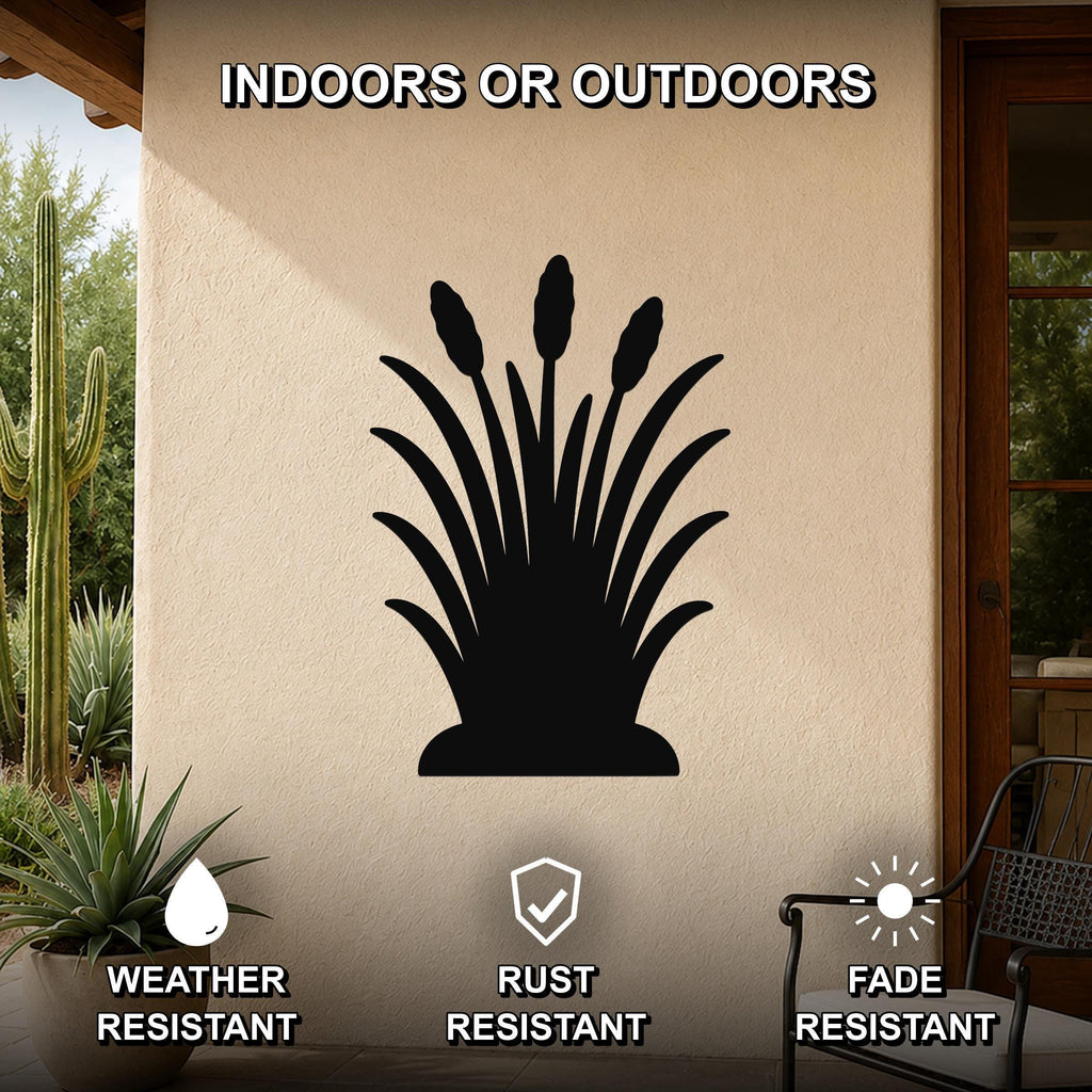Black metal wall art silhouette of wild grass with tall seed heads, mounted on an outdoor patio wall beside a cactus and potted plant.