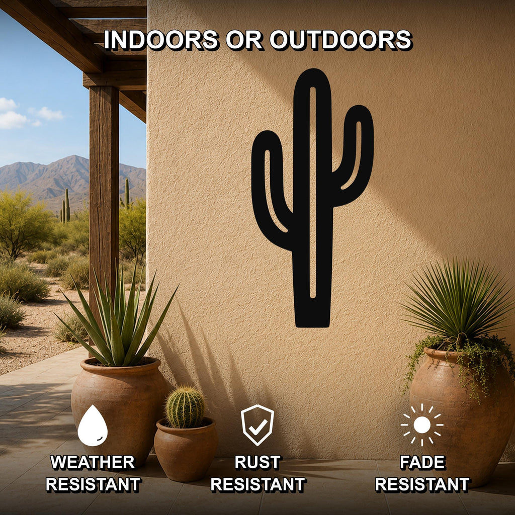 Black metal saguaro cactus wall art with cutout branches, mounted on a stucco outdoor wall above potted plants on a patio.