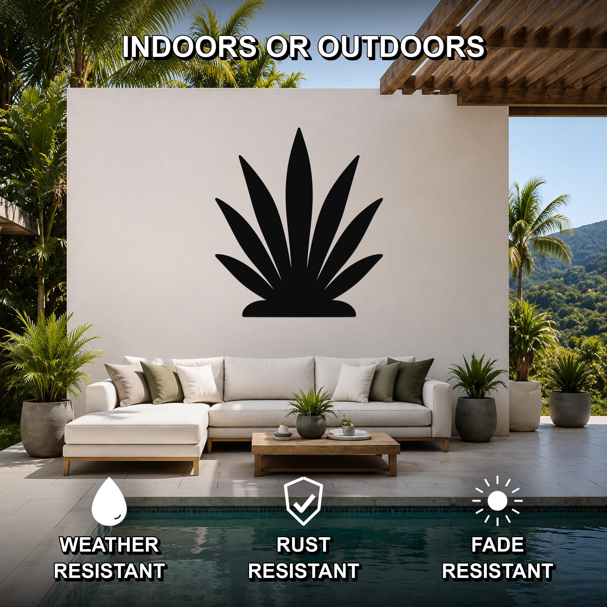 Black metal agave wall art silhouette mounted on a white outdoor wall above a white sectional sofa in a patio living area.
