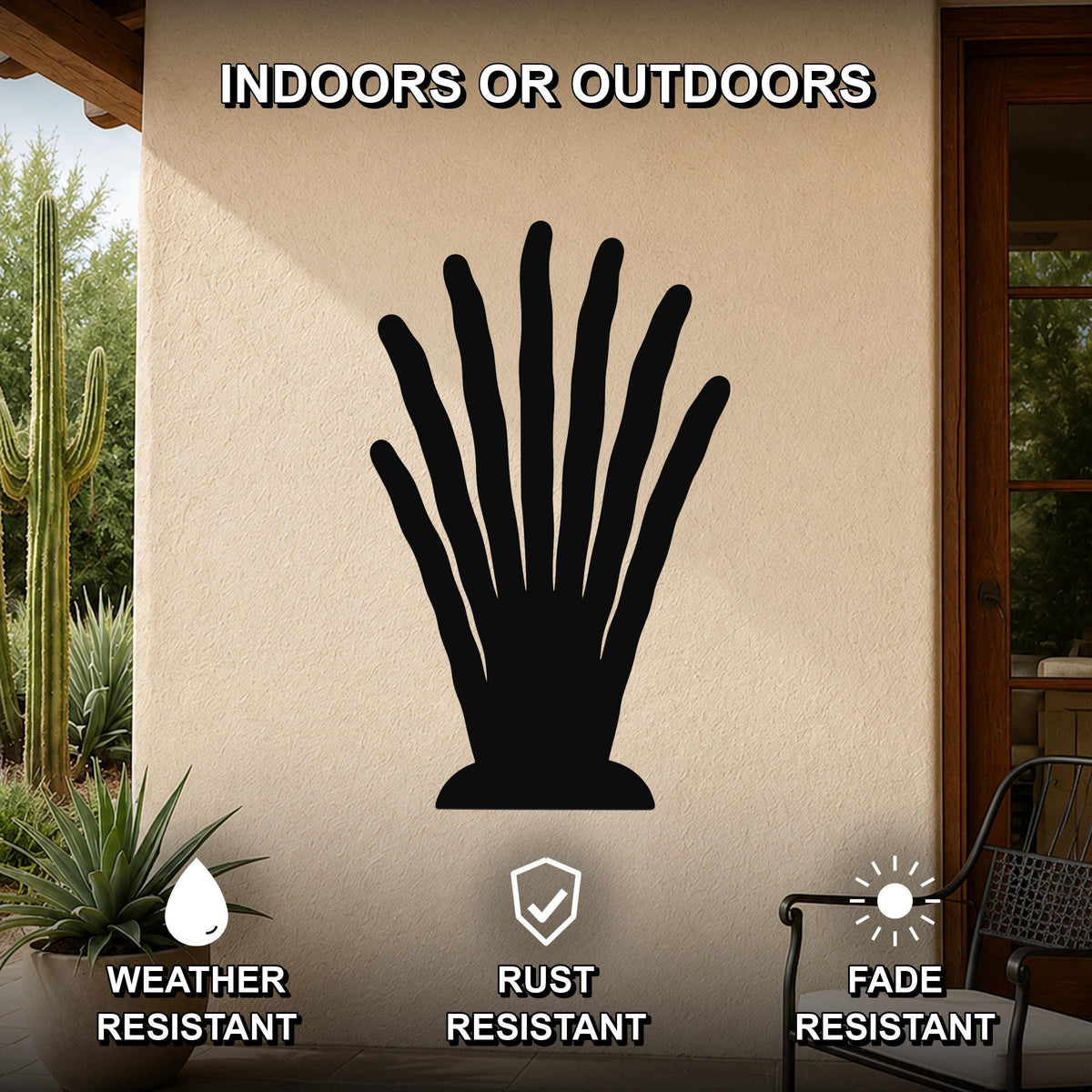 Black metal abstract plant wall art with finger-like cutouts, mounted on an outdoor patio wall with cacti and a chair visible nearby.