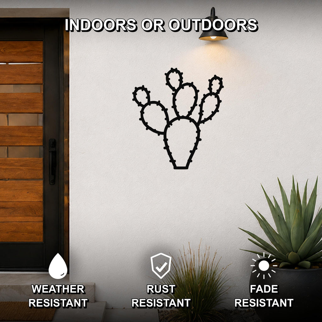 Black metal prickly pear cactus wall art with spiny cutout details, mounted on an outdoor wall beside a wooden door and potted plants.