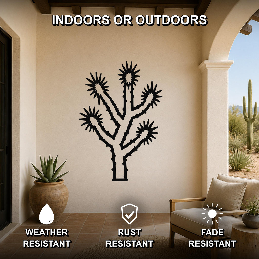 Black metal Joshua tree wall art with spiky branch cutouts, mounted on a beige patio wall above a wooden chair and potted plant.