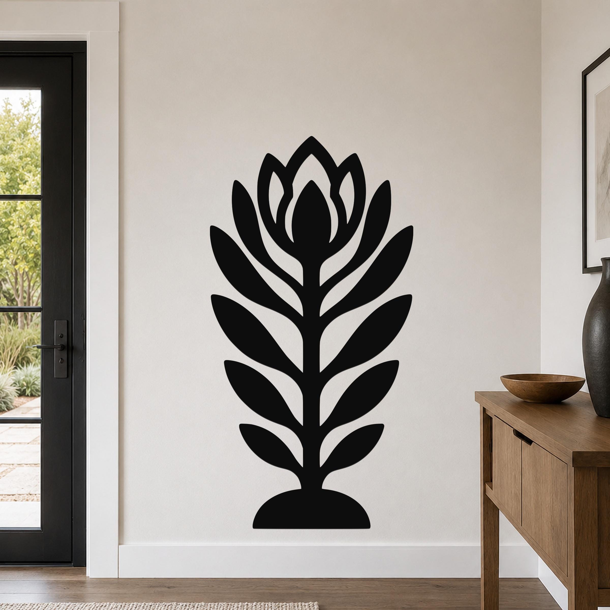 Black metal wall art in a stylized wildflower silhouette with layered petals and leaves, mounted on a living room wall above a wooden console table.