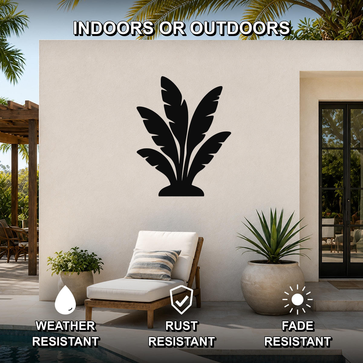 Black metal tropical leaves wall art silhouette mounted on an outdoor patio wall above a lounge chair, weather resistant, rust resistant, and fade resistant.