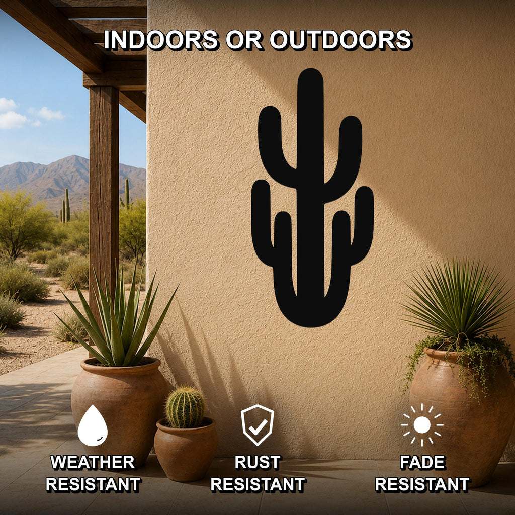 Black metal saguaro cactus wall art with cutout branches, mounted on a beige outdoor wall above potted plants on a patio.