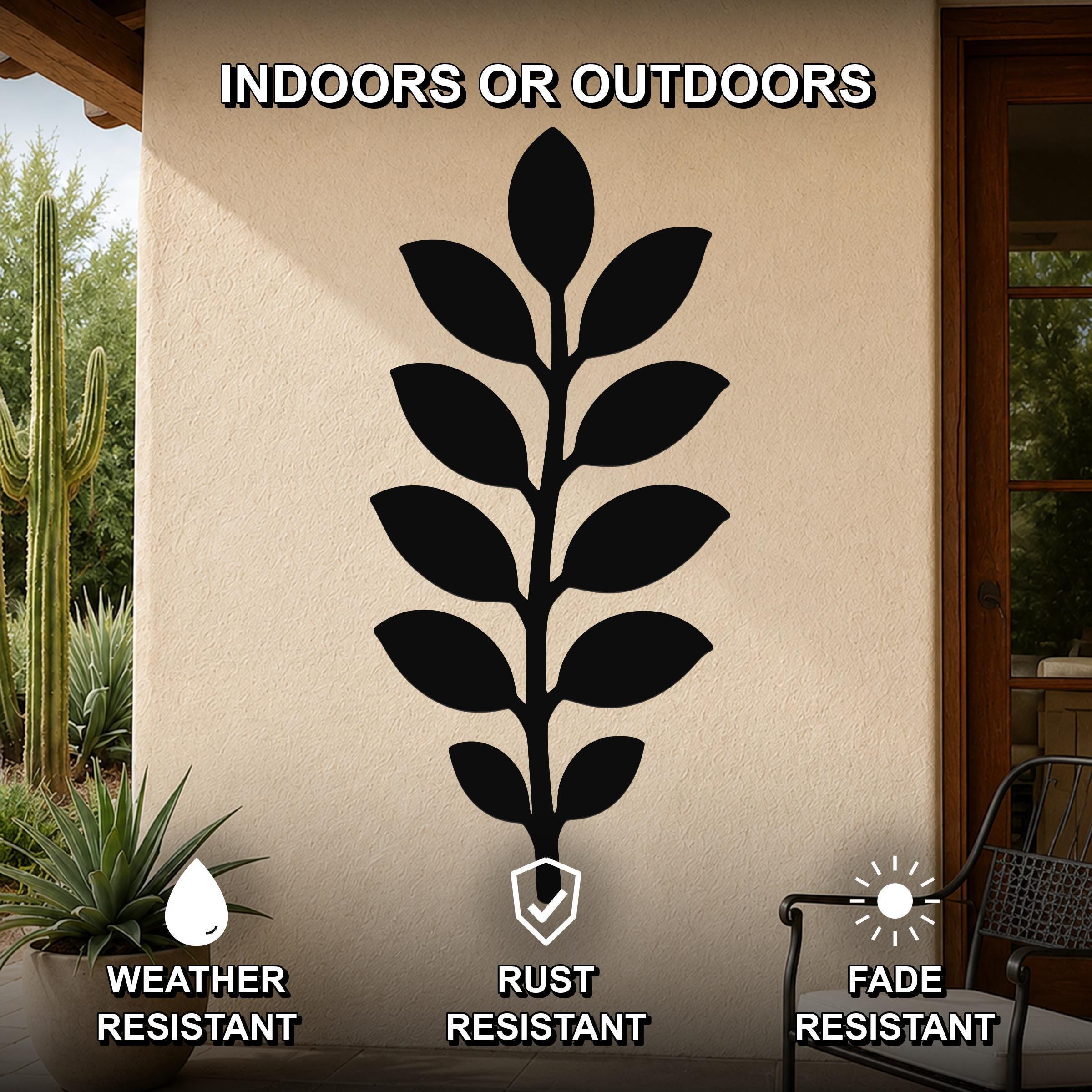 Black metal leaf wall art with a silhouette of a plant, mounted on an outdoor wall beside a patio door and potted plants.